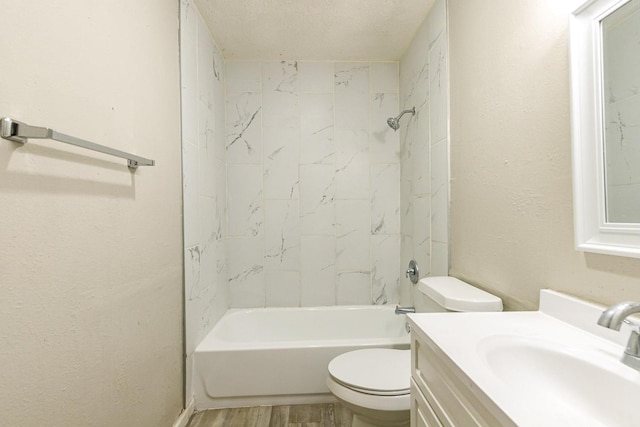 full bathroom featuring tiled shower / bath, wood-type flooring, vanity, toilet, and a textured ceiling