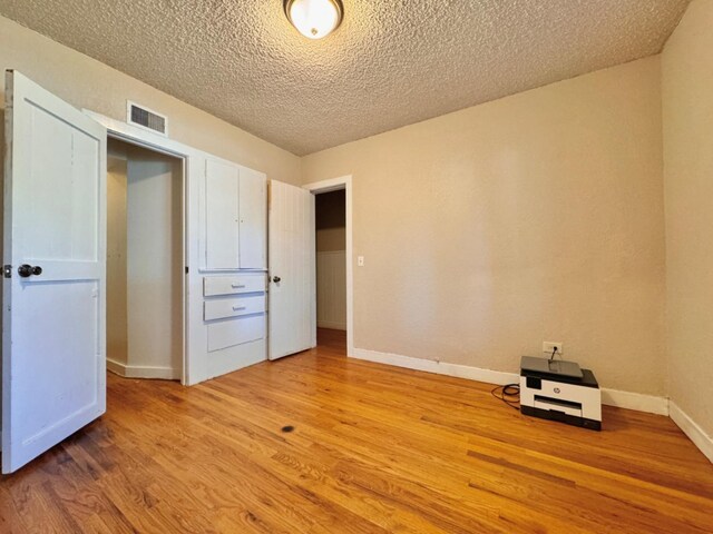 unfurnished bedroom with light hardwood / wood-style flooring and a textured ceiling