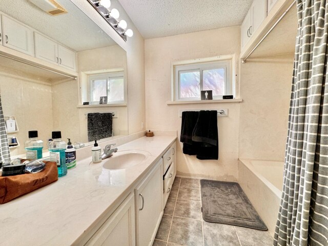 bathroom featuring tile patterned floors, shower / bathtub combination with curtain, vanity, and a textured ceiling