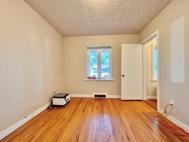 empty room with a textured ceiling and light wood-type flooring