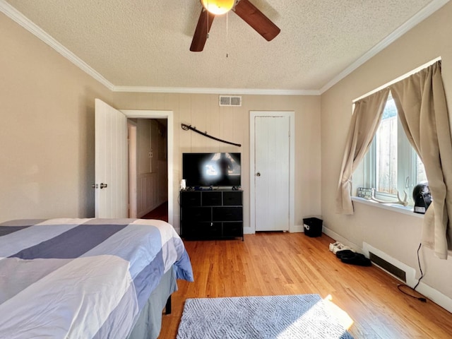 bedroom with crown molding, ceiling fan, wood-type flooring, and a textured ceiling