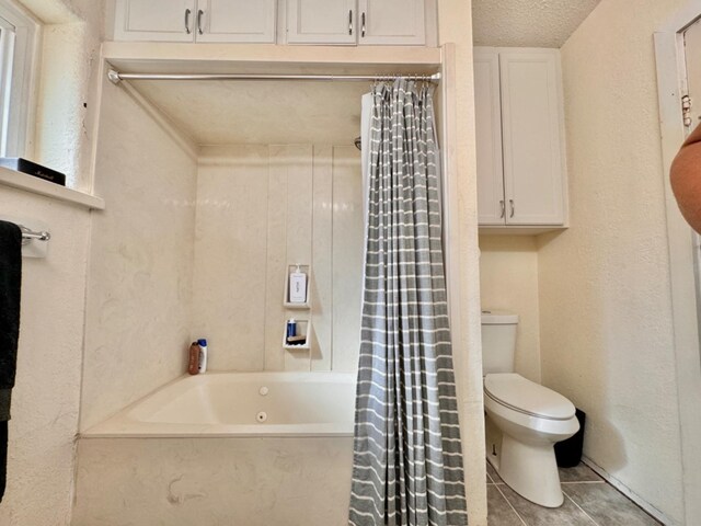 bathroom with a textured ceiling, tile patterned floors, toilet, and shower / bath combo