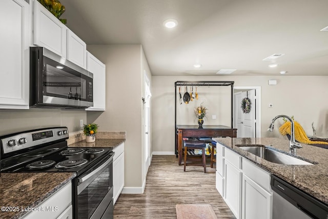 7533 33rd St, Lubbock, TX 79407 - kitchen with stainless steel appliances, a sink, wood finished floors, white cabinetry, and dark stone countertops