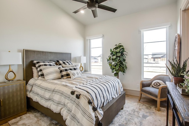 bedroom with ceiling fan, vaulted ceiling, and light wood-type flooring