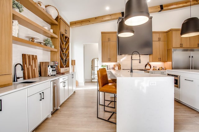 kitchen featuring pendant lighting, stainless steel built in fridge, sink, and white cabinets