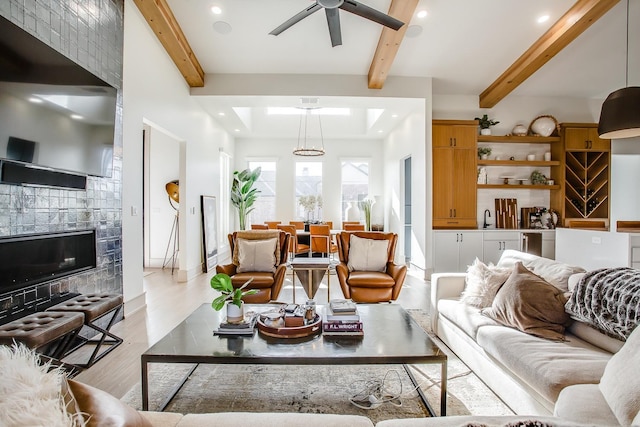 living room with beam ceiling, ceiling fan, and light wood-type flooring