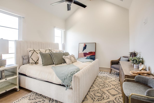 bedroom with ceiling fan, high vaulted ceiling, and light wood-type flooring