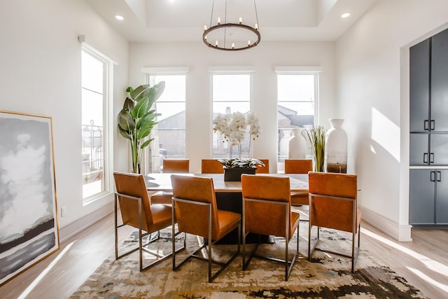 dining area with a healthy amount of sunlight, a notable chandelier, and a tray ceiling