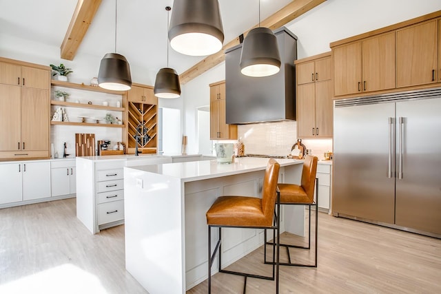 kitchen featuring extractor fan, a kitchen island, decorative light fixtures, white cabinetry, and stainless steel built in fridge