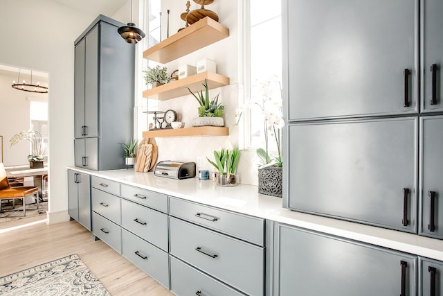 bar with gray cabinetry, backsplash, and light hardwood / wood-style floors