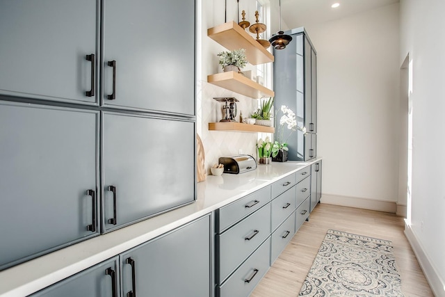 interior space featuring backsplash, light hardwood / wood-style flooring, and gray cabinetry