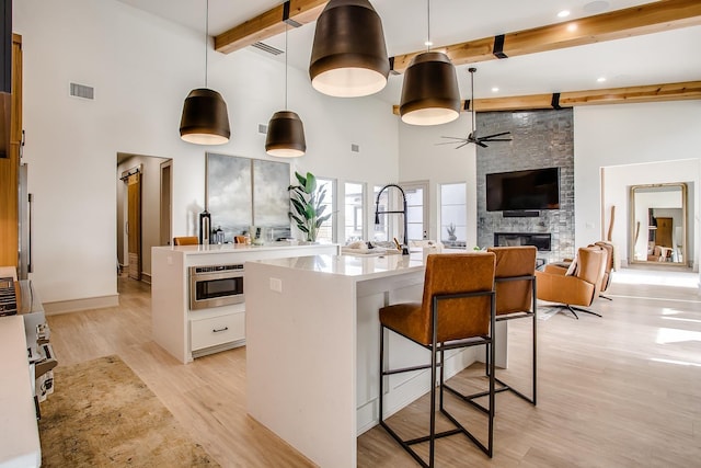 kitchen with a center island with sink, white cabinetry, pendant lighting, and light hardwood / wood-style floors