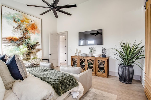 bedroom featuring light hardwood / wood-style flooring, ceiling fan, and a high ceiling