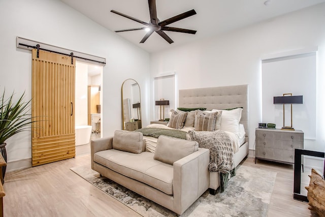 bedroom with lofted ceiling, light hardwood / wood-style flooring, a barn door, and ceiling fan