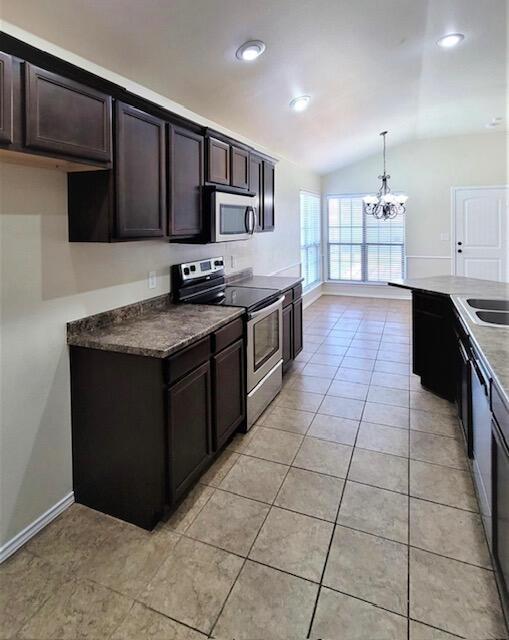 kitchen featuring lofted ceiling, stainless steel appliances, dark brown cabinets, baseboards, and a notable chandelier