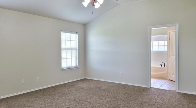 spare room featuring lofted ceiling, ceiling fan, light colored carpet, and a healthy amount of sunlight