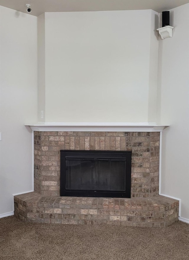 interior details with a brick fireplace, carpet flooring, and baseboards