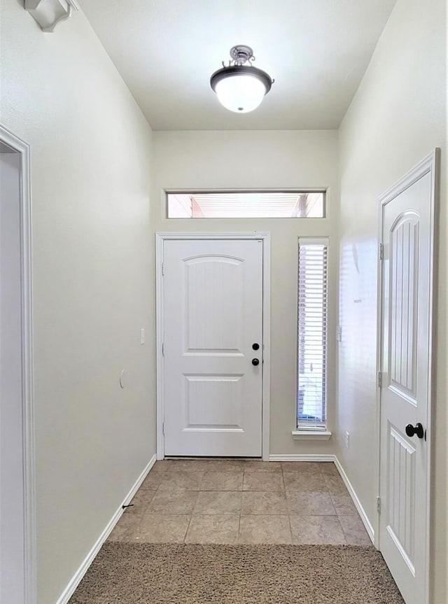 doorway to outside with light tile patterned floors and baseboards