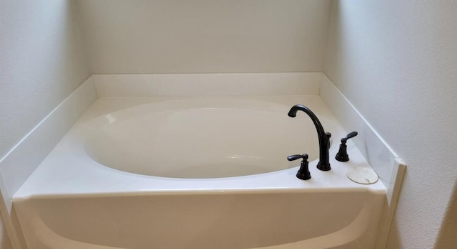interior details with a garden tub and a textured wall