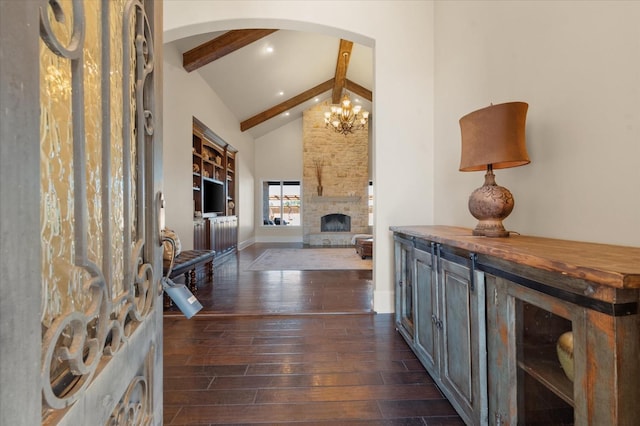 foyer entrance featuring a stone fireplace, an inviting chandelier, high vaulted ceiling, dark hardwood / wood-style floors, and beamed ceiling