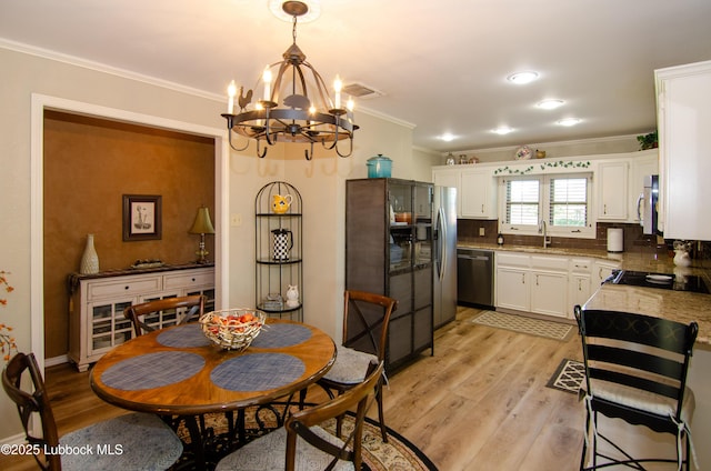 12220 Chicago Ave, Lubbock, TX 79424 - kitchen with stainless steel appliances, a chandelier, ornamental molding, white cabinets, and light wood-style floors