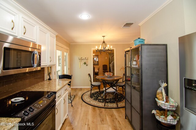 12220 Chicago Ave, Lubbock, TX 79424 - kitchen featuring stainless steel appliances, french doors, light wood-style floors, white cabinetry, and ornamental molding