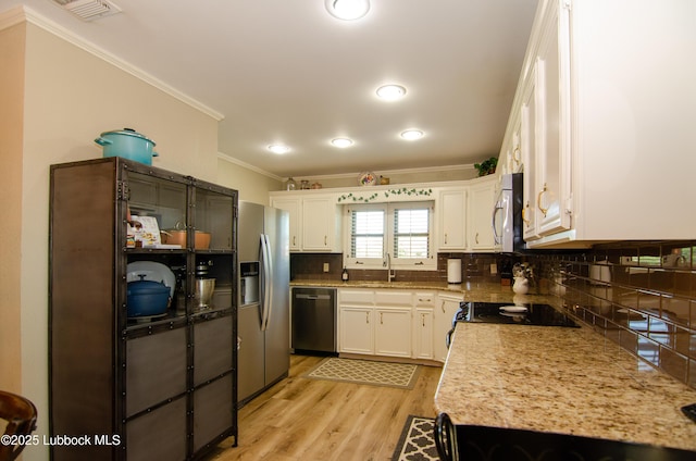 12220 Chicago Ave, Lubbock, TX 79424 - kitchen featuring stainless steel appliances, crown molding, decorative backsplash, light wood-style flooring, and white cabinetry