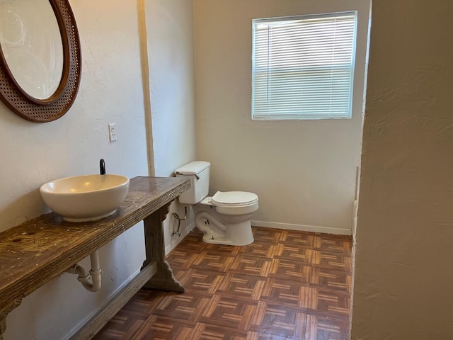 bathroom with parquet flooring, sink, and toilet