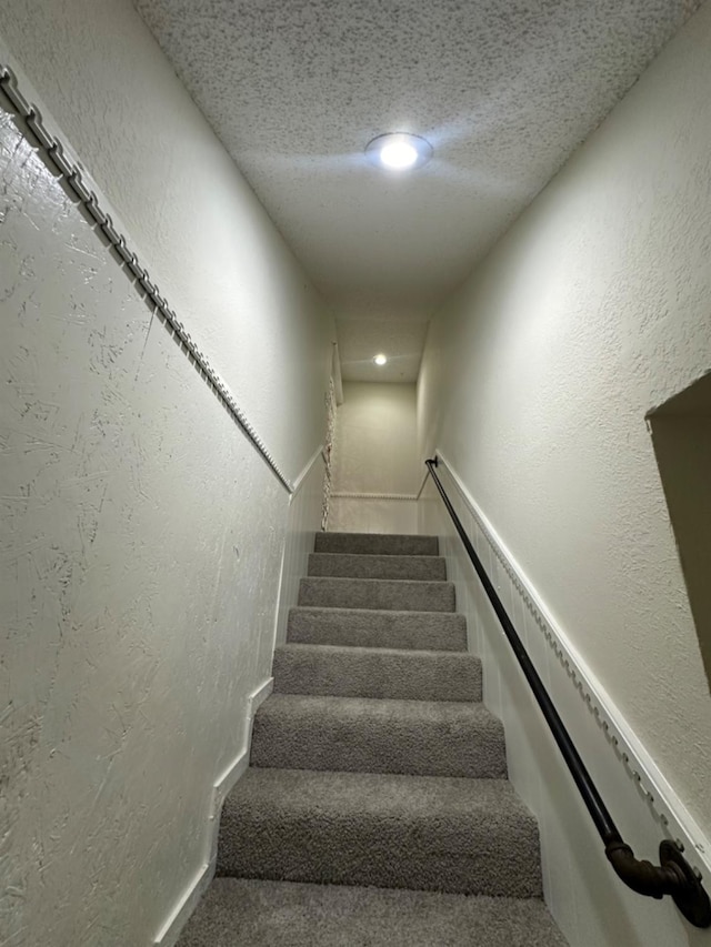 staircase featuring a textured ceiling