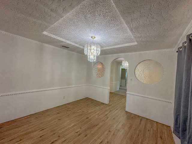 empty room with crown molding, wood-type flooring, an inviting chandelier, and a textured ceiling