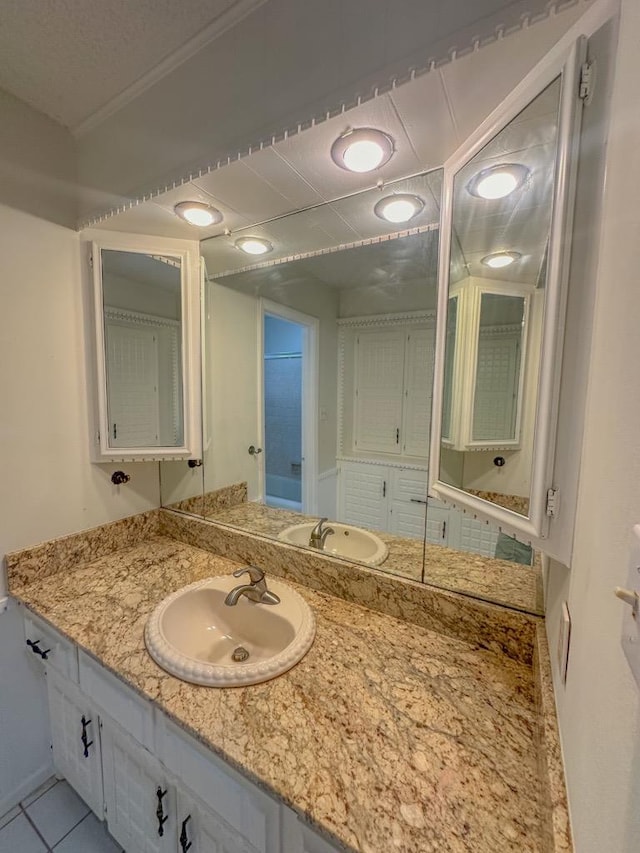 bathroom with crown molding, tile patterned floors, vanity, and a textured ceiling