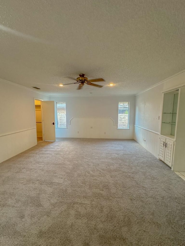 spare room featuring ceiling fan, plenty of natural light, carpet flooring, and a textured ceiling