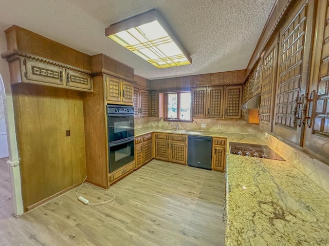 kitchen featuring sink, black appliances, light stone countertops, a textured ceiling, and light wood-type flooring