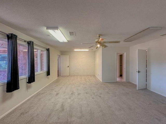 spare room with ceiling fan, brick wall, light colored carpet, and a textured ceiling