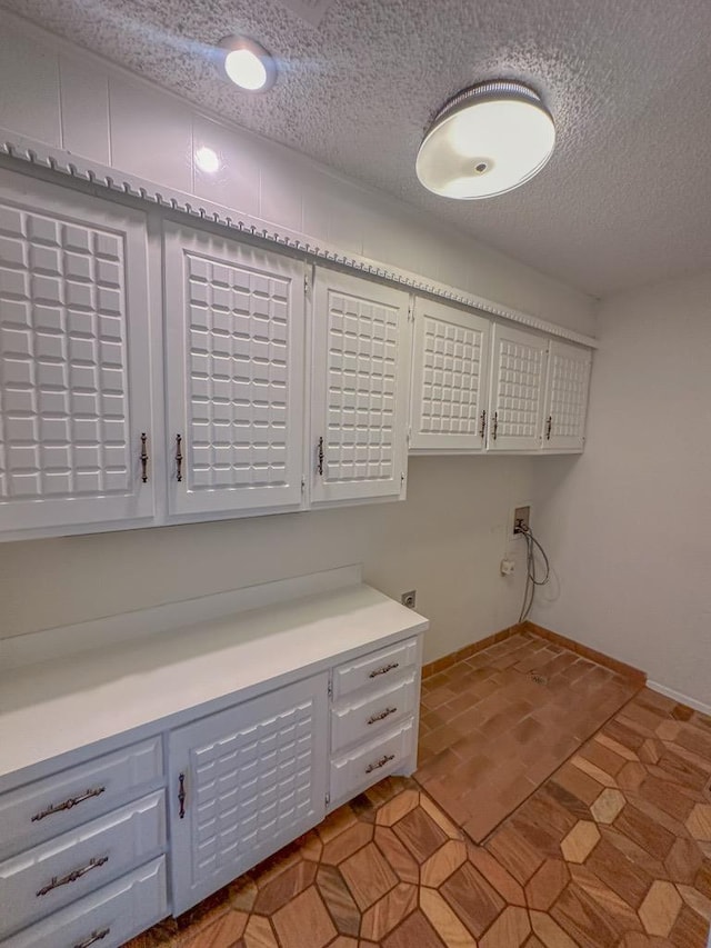 washroom featuring washer hookup, electric dryer hookup, cabinets, and a textured ceiling