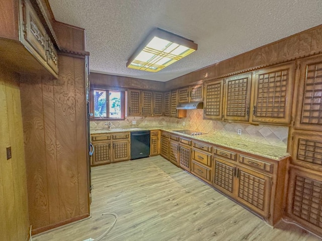 kitchen with black appliances, a textured ceiling, light wood-type flooring, light stone countertops, and backsplash