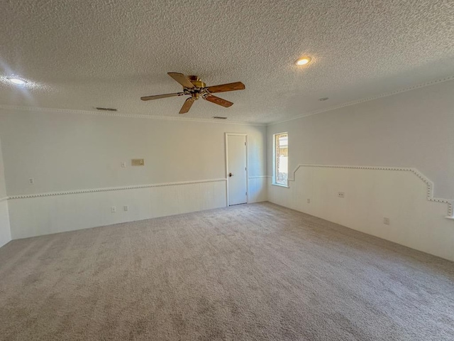 carpeted spare room featuring crown molding, ceiling fan, and a textured ceiling