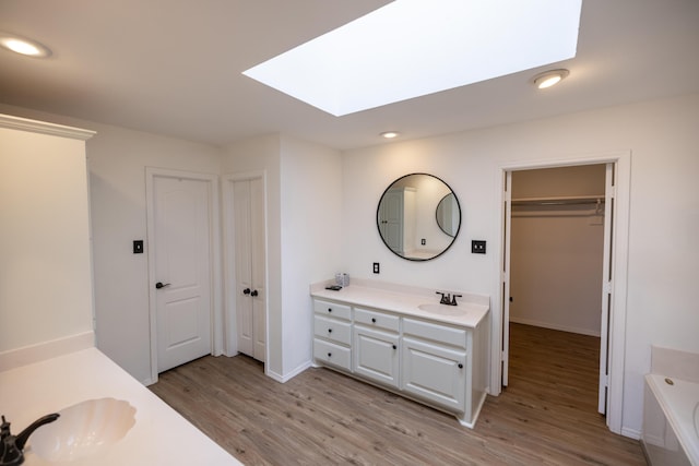 544 S US Highway 87, Wilson, TX 79381 - bathroom featuring a skylight, wood finished floors, vanity, a bathing tub, and recessed lighting