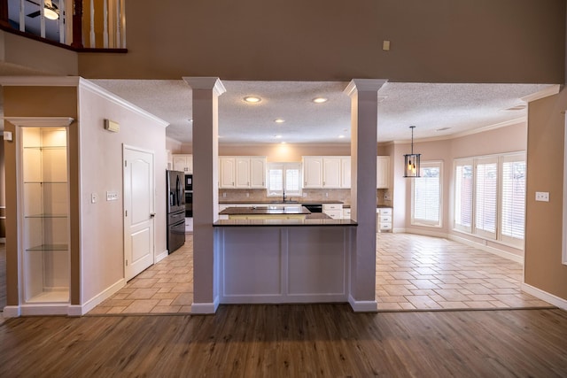 544 S US Highway 87, Wilson, TX 79381 - kitchen with ornate columns, ornamental molding, a wealth of natural light, and white cabinetry