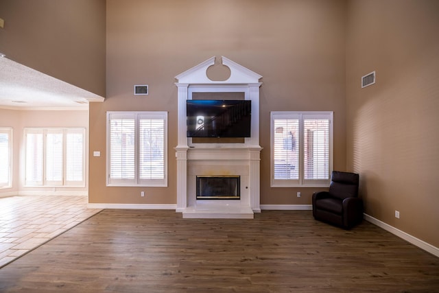 544 S US Highway 87, Wilson, TX 79381 - unfurnished living room featuring a high ceiling, visible vents, wood finished floors, and a fireplace