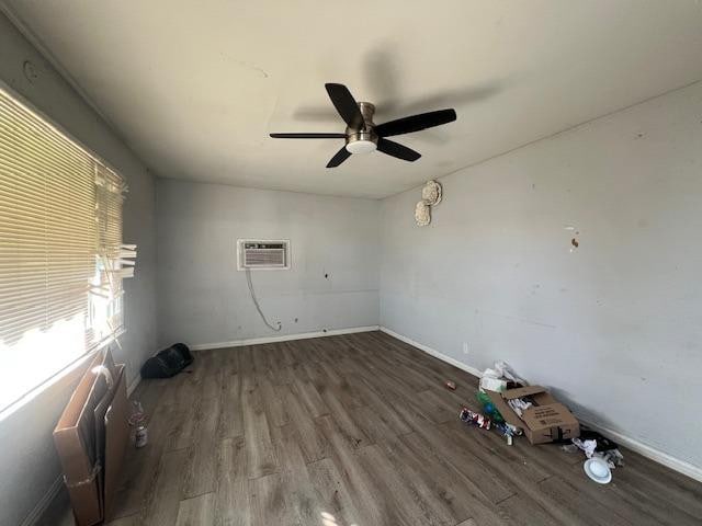 empty room featuring wood-type flooring, a wall mounted AC, and ceiling fan