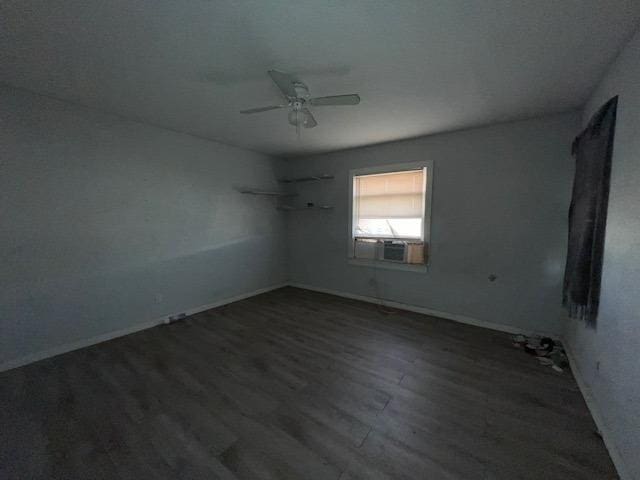 empty room featuring dark wood-type flooring, ceiling fan, and cooling unit