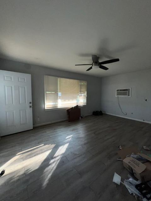 interior space with ceiling fan, dark hardwood / wood-style flooring, and a wall mounted AC