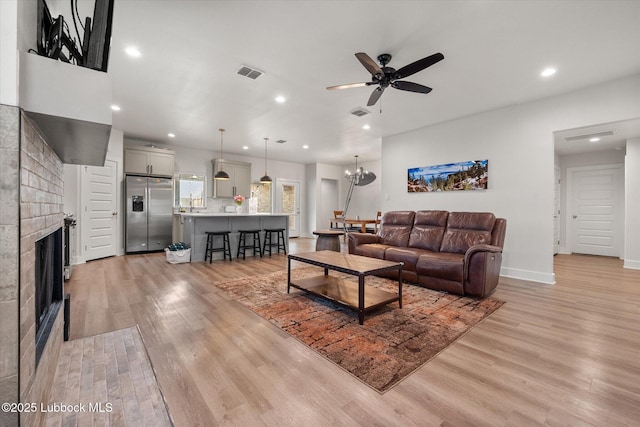 4724 121st Pl, Lubbock, TX 79424 - living room with light wood-style flooring, a tile fireplace, recessed lighting, a ceiling fan, and baseboards