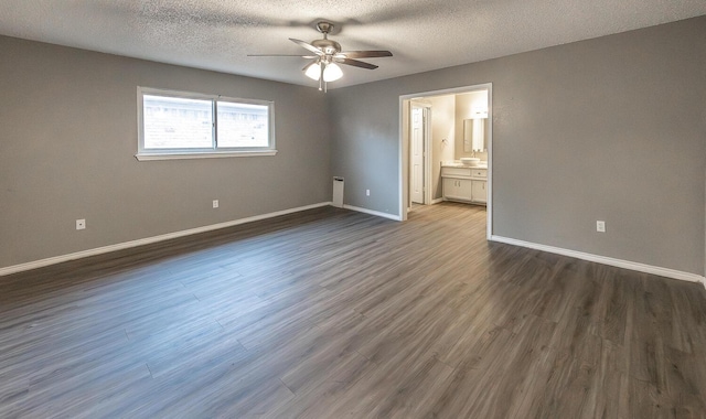 unfurnished bedroom featuring ceiling fan, dark wood-type flooring, ensuite bathroom, and a textured ceiling