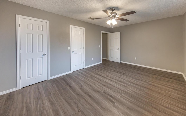 unfurnished bedroom featuring ceiling fan, a textured ceiling, and dark hardwood / wood-style flooring