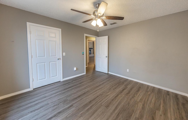 unfurnished bedroom featuring ceiling fan, dark wood-type flooring, and a textured ceiling