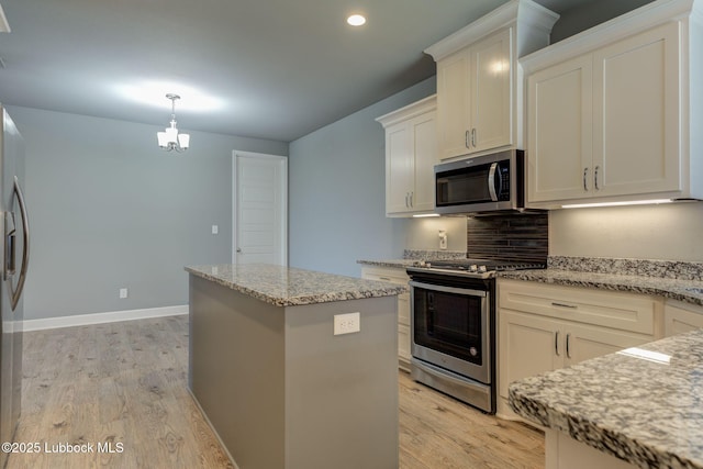 136 Preston Hollow Ln, Wolfforth, TX 79382 - kitchen with stainless steel appliances, light wood-type flooring, a center island, light stone countertops, and white cabinetry