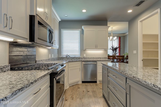 136 Preston Hollow Ln, Wolfforth, TX 79382 - kitchen with appliances with stainless steel finishes, a chandelier, light wood-type flooring, white cabinets, and recessed lighting