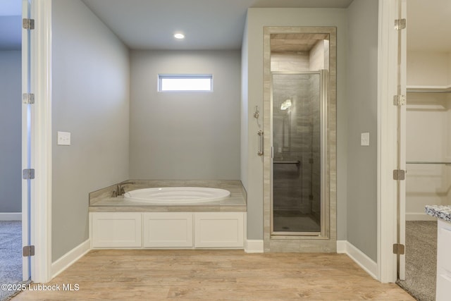 136 Preston Hollow Ln, Wolfforth, TX 79382 - bathroom featuring a shower stall, a garden tub, a spacious closet, wood finished floors, and recessed lighting